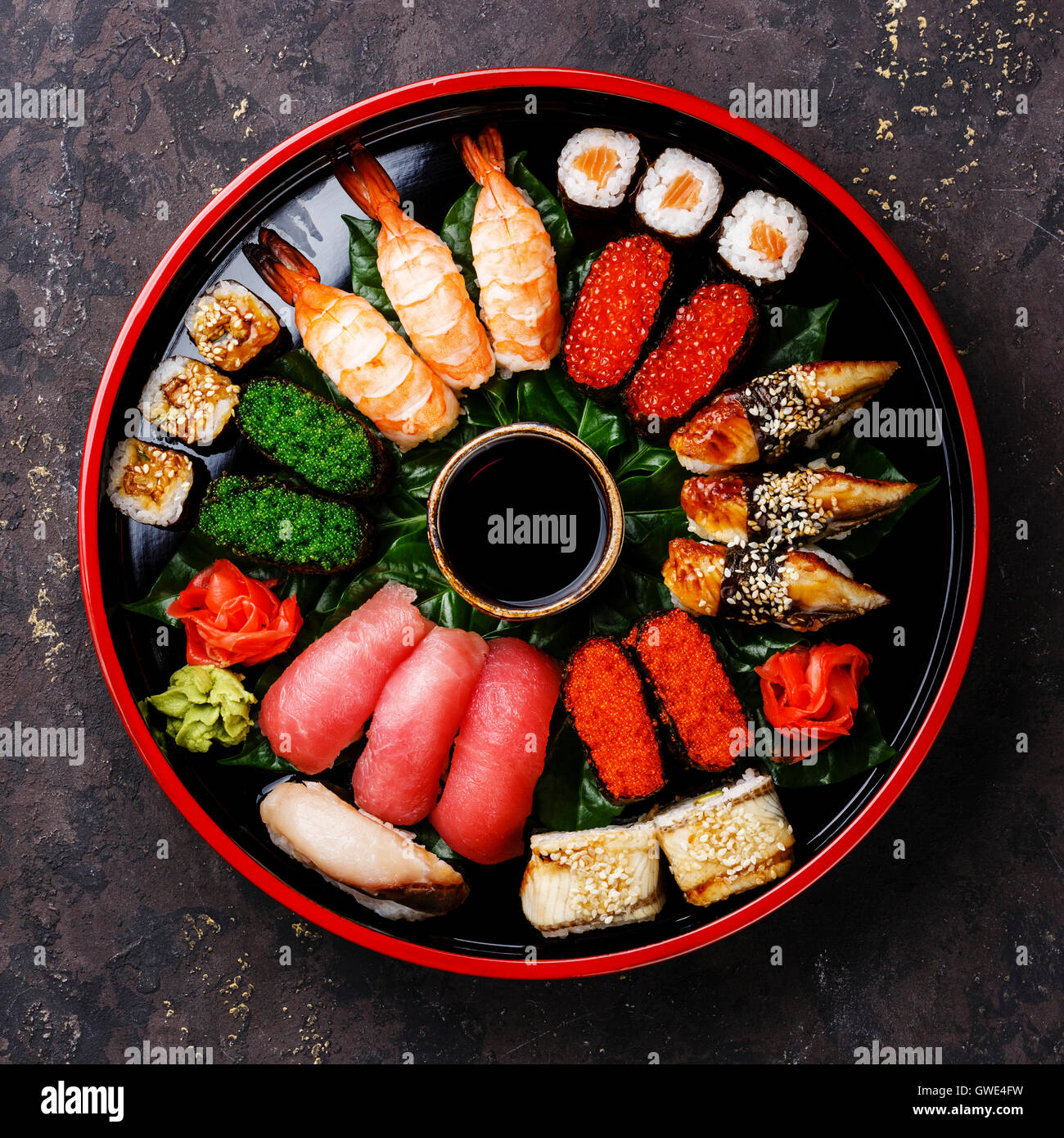 Sushi Set nigiri, rolls, gunkan and sashimi served in traditional Japan black Sushioke round plate Stock Photo