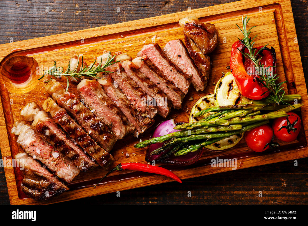 Sliced grilled Black Angus Steak Striploin and vegetables on cutting board  close up Stock Photo - Alamy