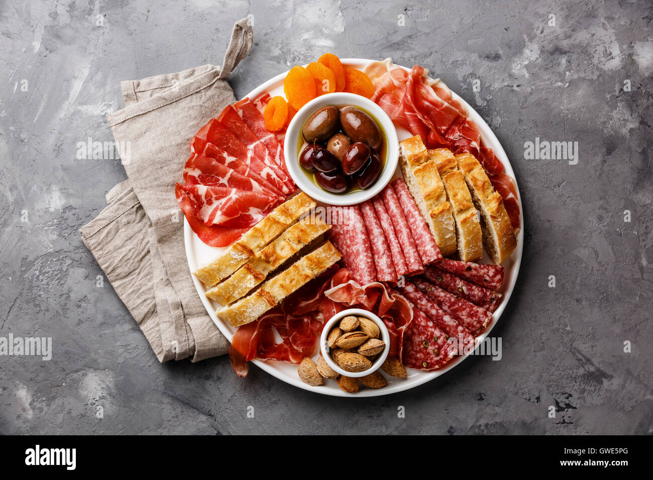 Cold meat plate with prosciutto, salami, ciabatta bread and olives on gray concrete stone background Stock Photo
