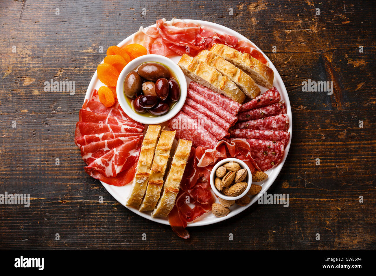 Cold meat plate with prosciutto, salami, ciabatta bread and olives on wooden background Stock Photo