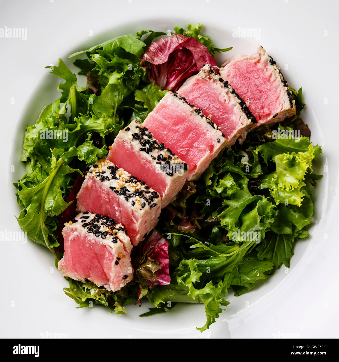 Sliced grilled Tuna steak in sesame on Green salad close up Stock Photo