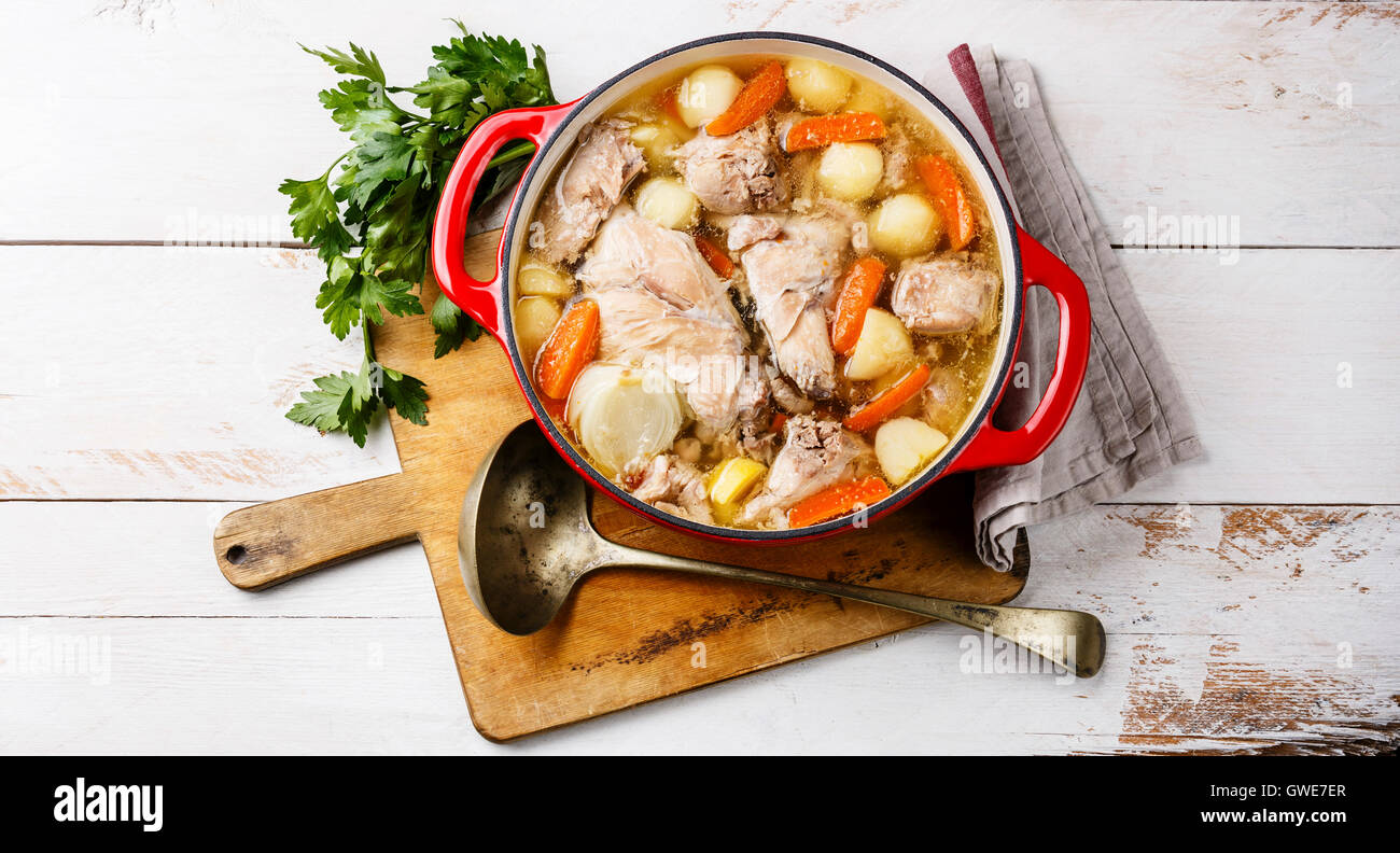 Stewed rabbit with potatoes and carrot in cast iron pot on rustic wooden table background Stock Photo