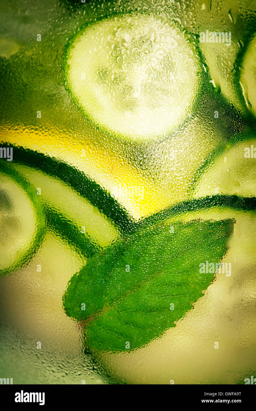 Infused water with cucumber, lemon, lime and mint on blue background Stock Photo