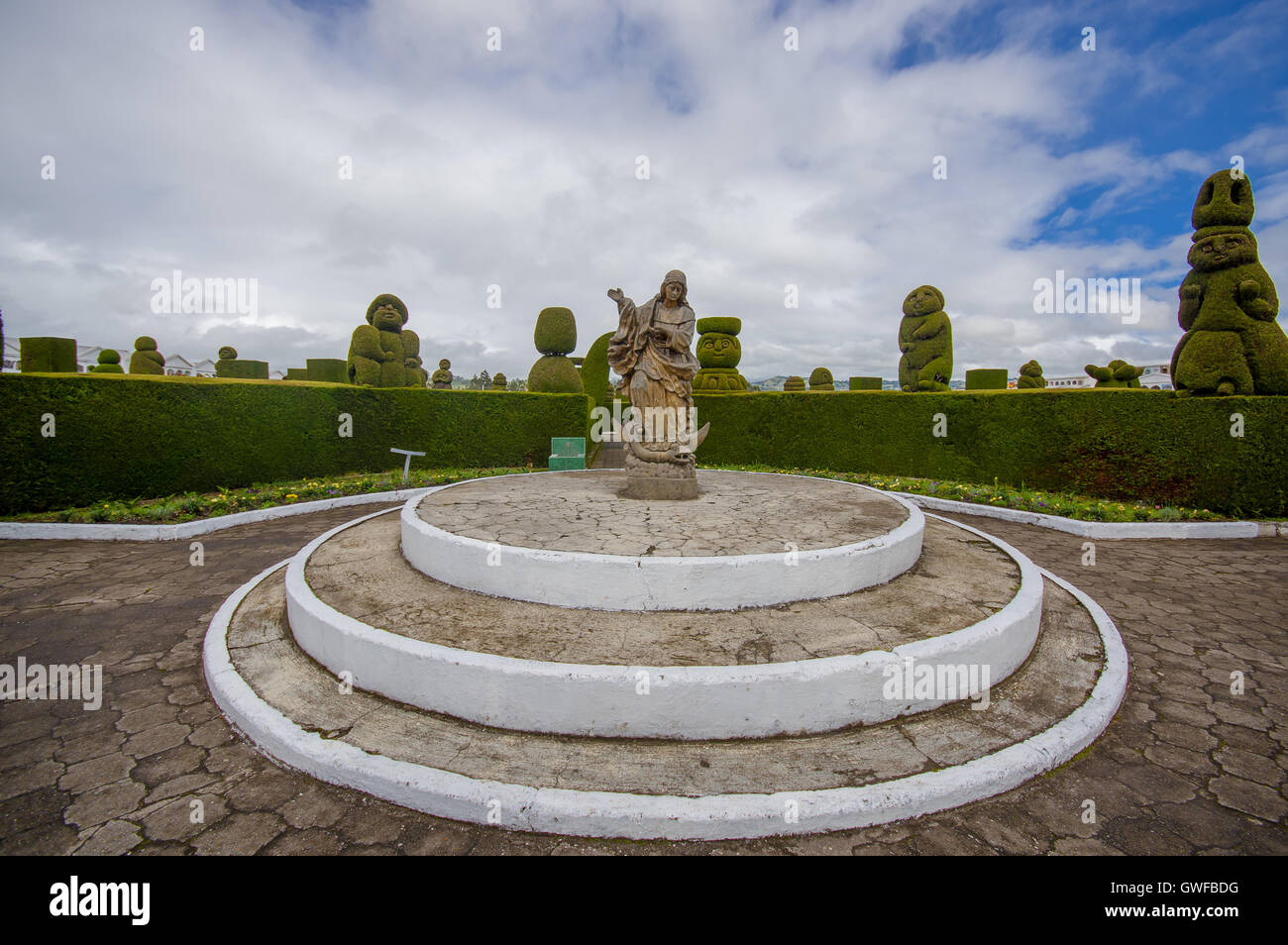 TULCAN, ECUADOR - JULY 3, 2016: statue of an angel standing over a demon in the center of the cemetery surrounded by plants sculptures Stock Photo
