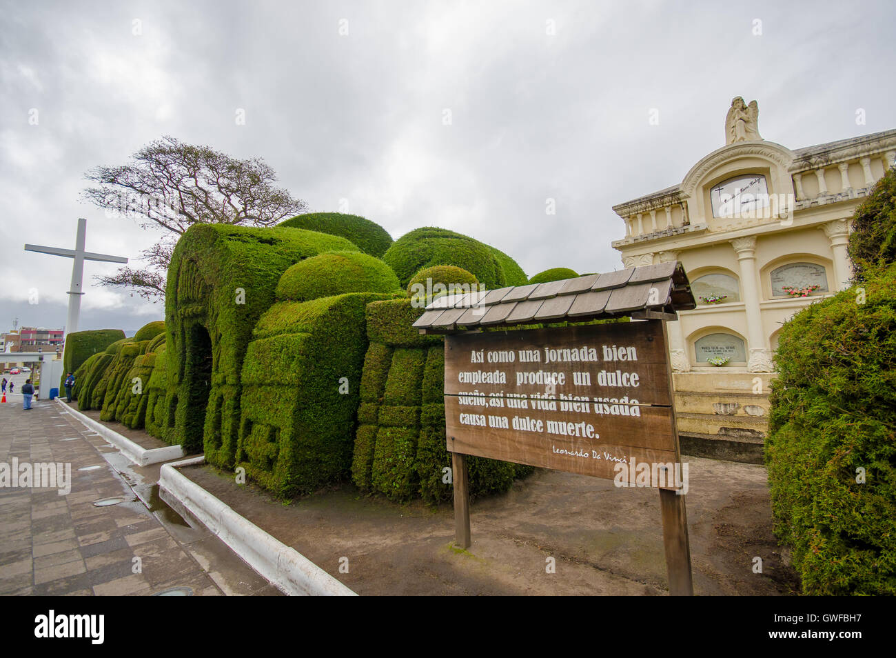TULCAN, ECUADOR - JULY 3, 2016: some plants sculptures at the entrance of the cemetery next to a wood sign with a phrase on it Stock Photo