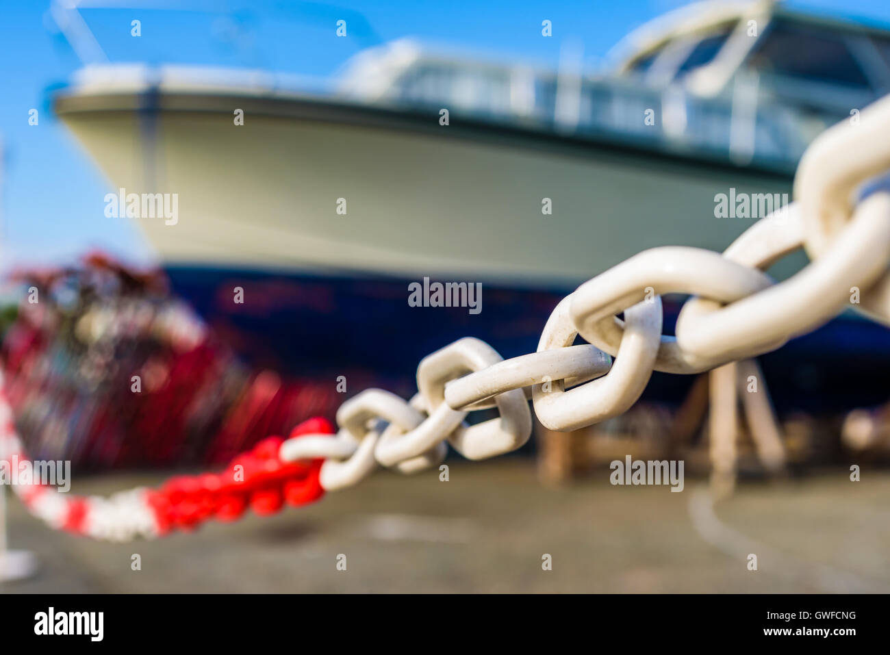 Narrow focus on white and red plastic chain with large blurred motorboat in background. Stock Photo