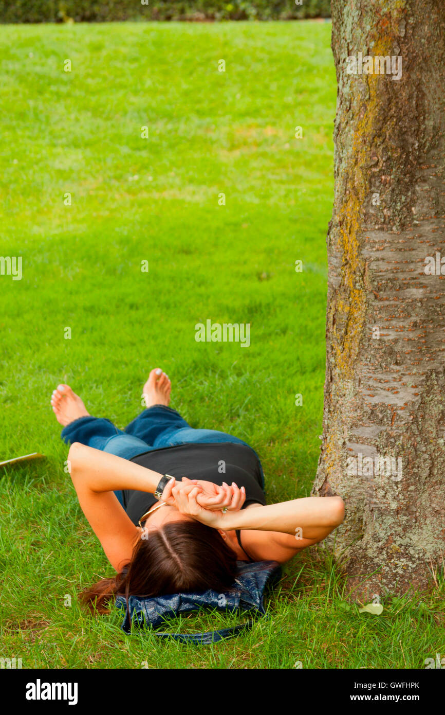 Young female relaxing on the lawn in the park Stock Photo - Alamy