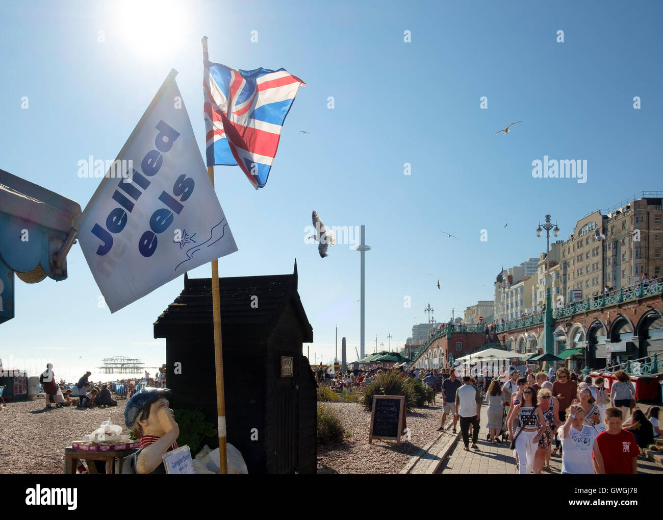 Jellied eels, burned out pier, Union Jack, i360 tower, hordes of visitors, sun and seagulls on promenade in Brighton Stock Photo