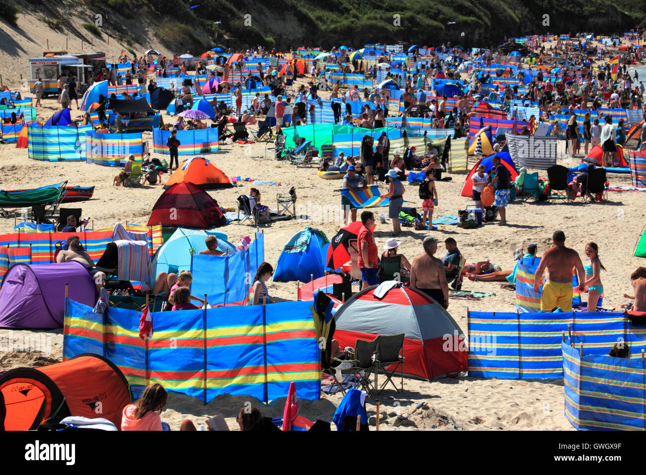 A beach crowded with holidaymakers and windbreaks at Harlyn Bay, North Cornwall. Stock Photo