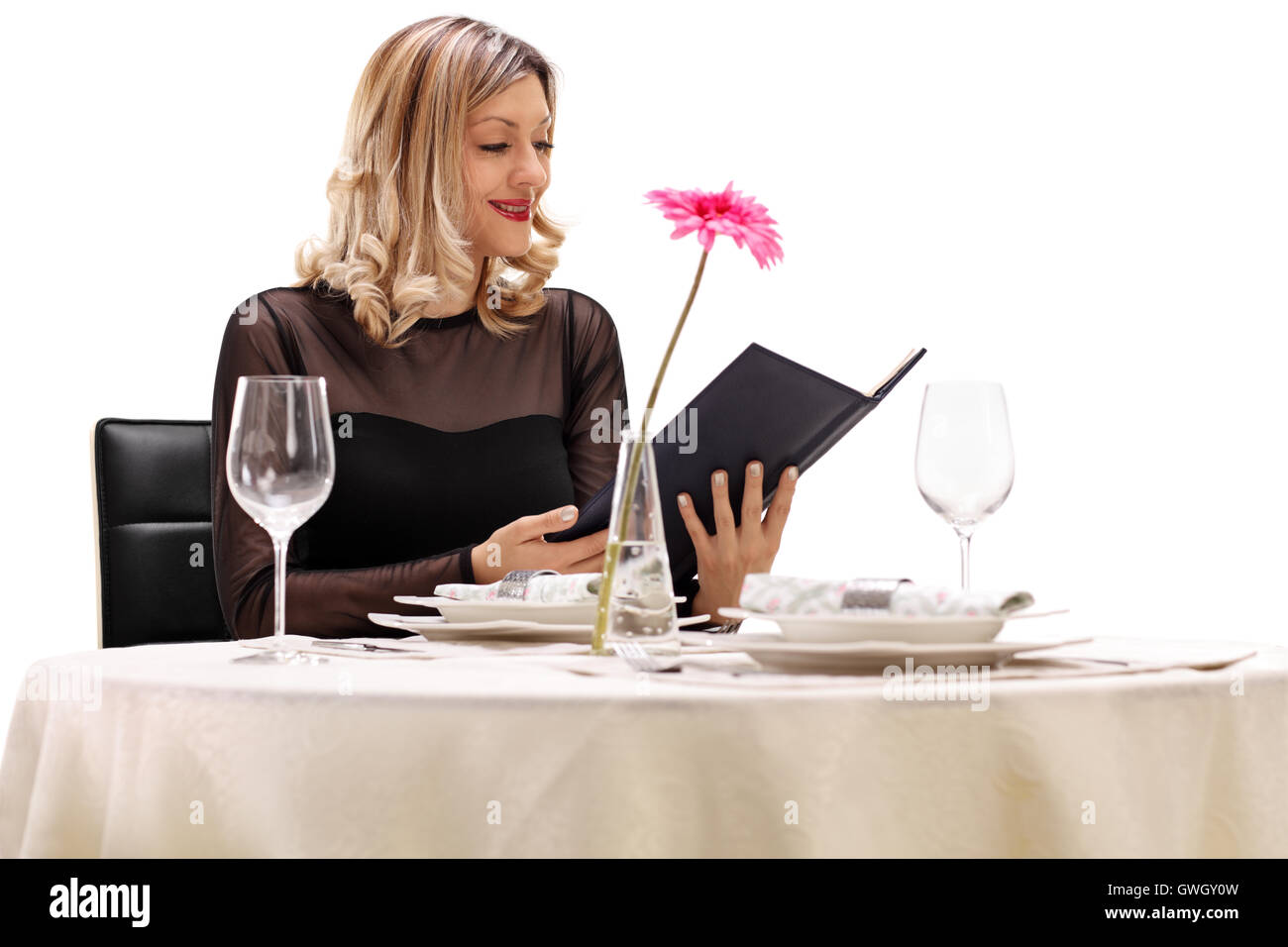 Young woman sitting at a restaurant table and reading the menu isolated on white background Stock Photo