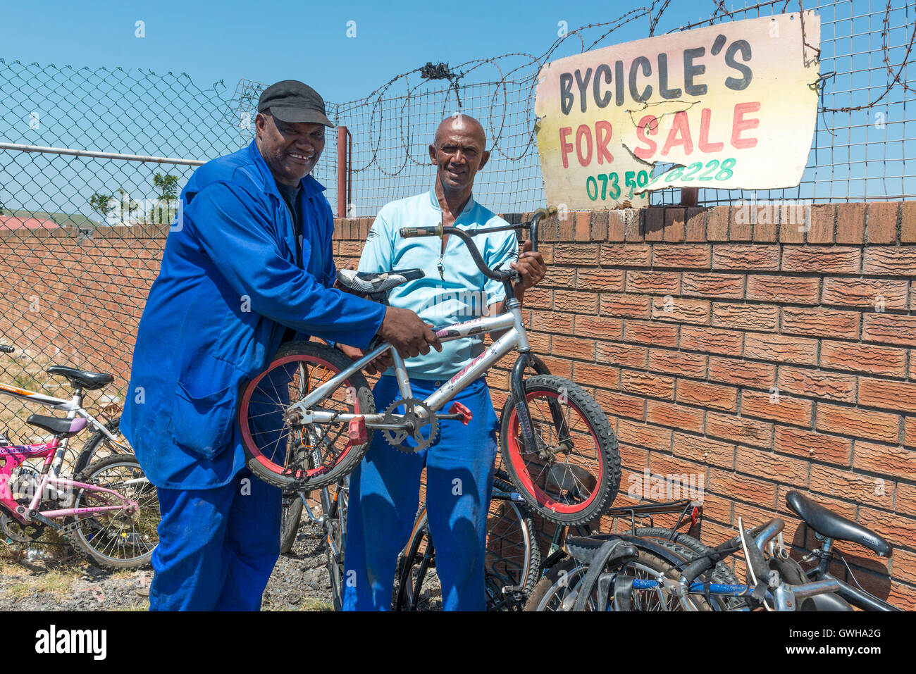 Bicycle mechanic selling a child's bike to a customer, Cape Town, South