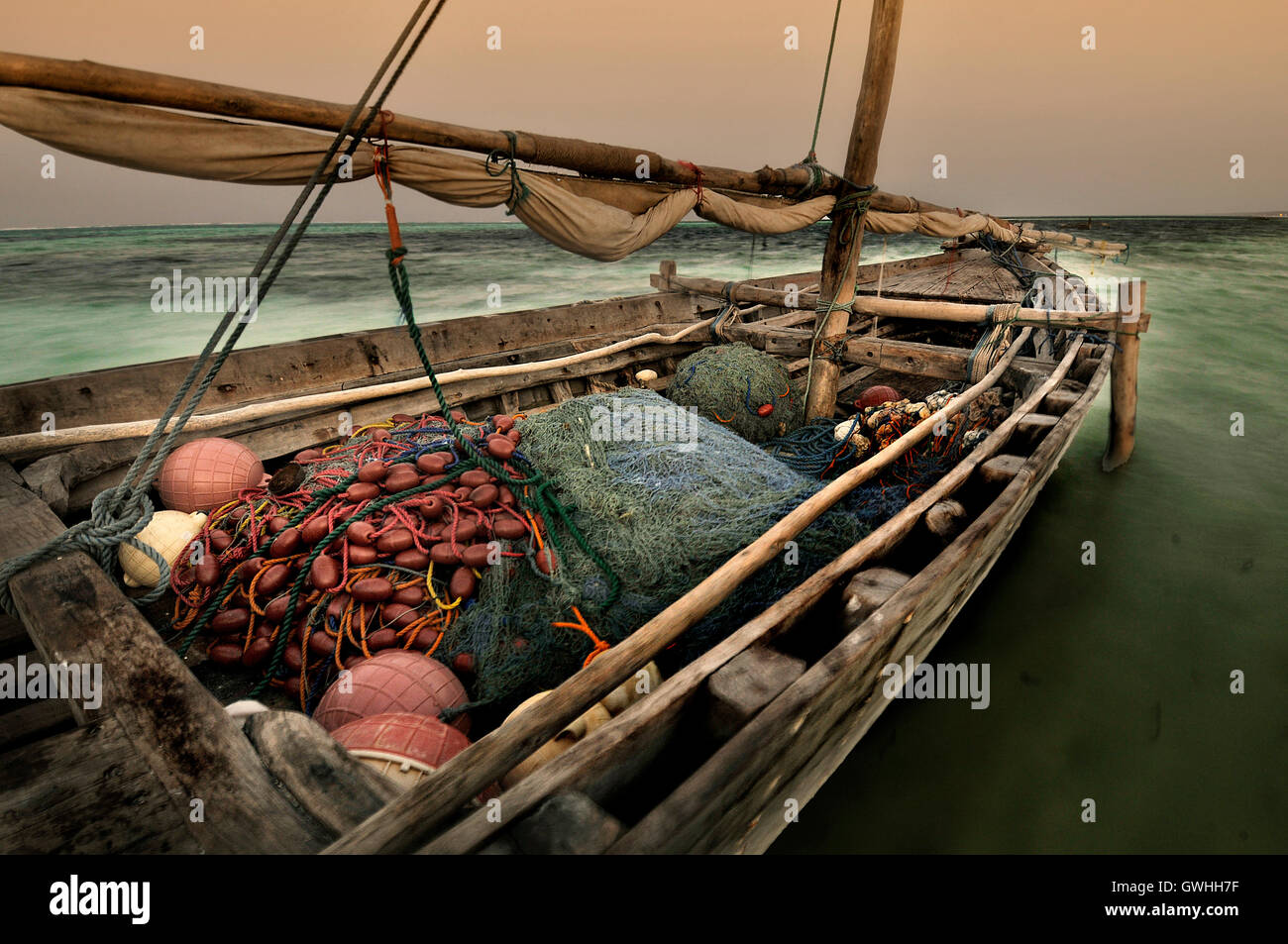An old wooden fishing boat with nets on the ocean at sunset Stock Photo ...