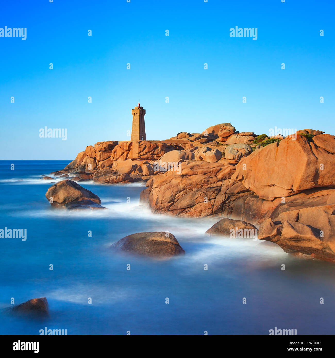 Ploumanach Mean Ruz lighthouse red sunset in pink granite coast, Perros Guirec, Brittany, France. Long exposure. Stock Photo