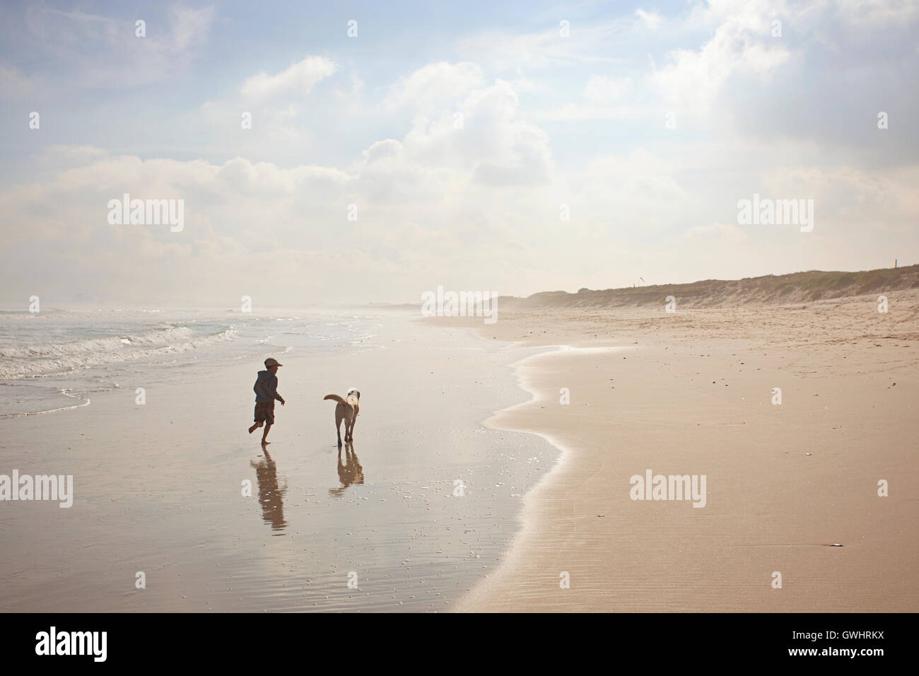 Young boy running dog on the beach, Milnerton Beach, South Africa Stock Photo