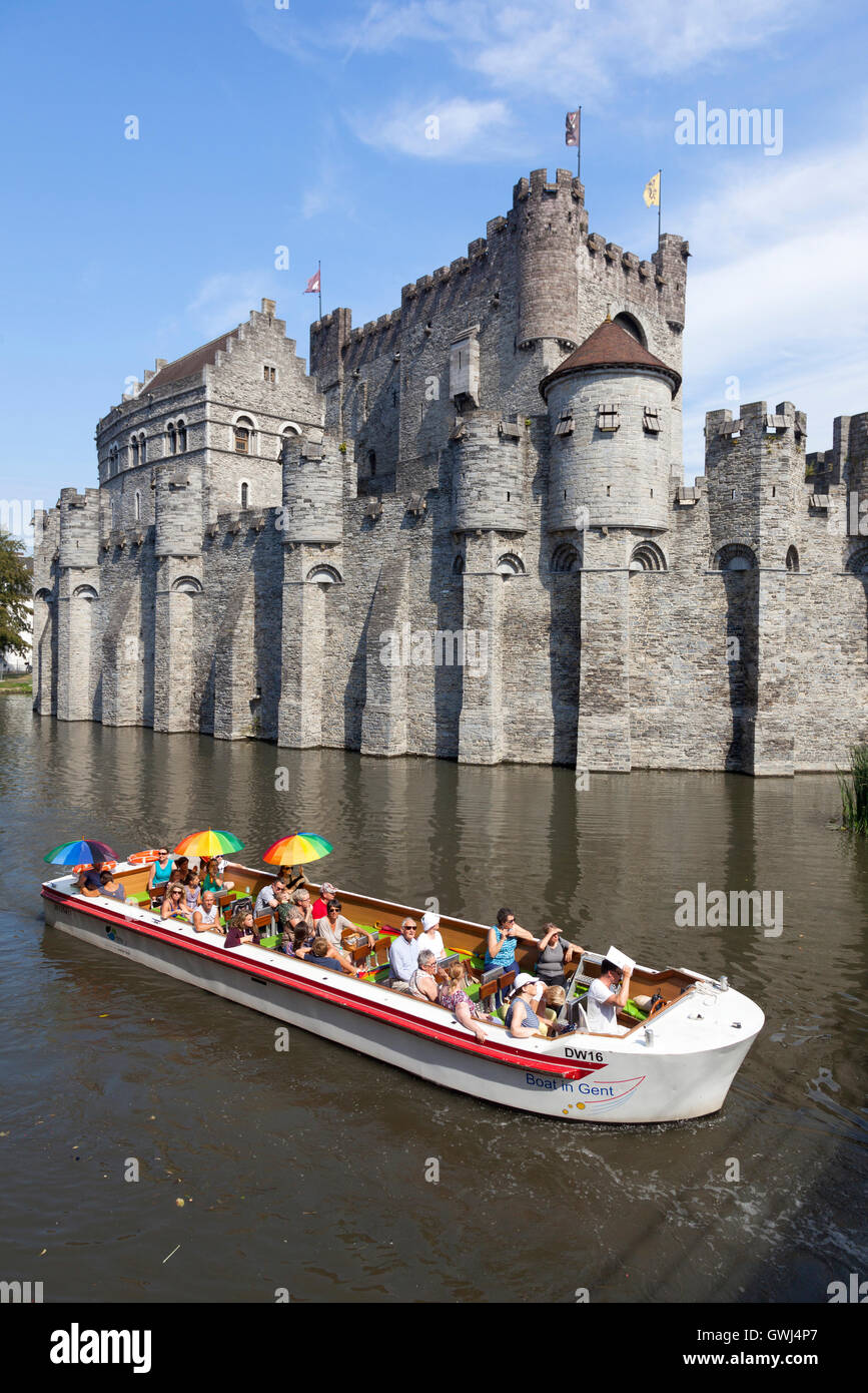 tourist boat full of colorful people on river near Gravenstein Castle in belgian medieval city centre of Ghent Stock Photo