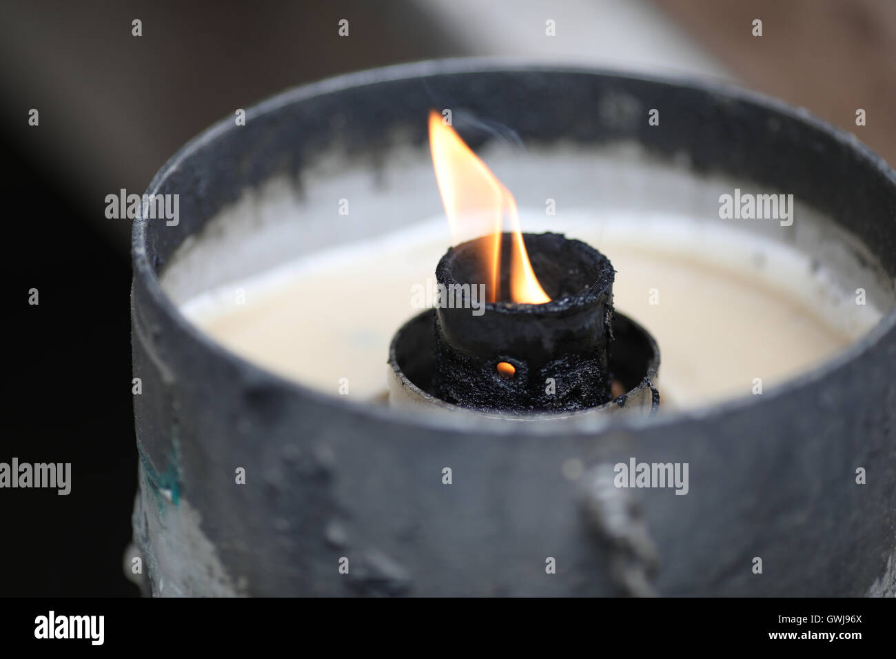 A small candle's flame burning surrounded by metal. Stock Photo