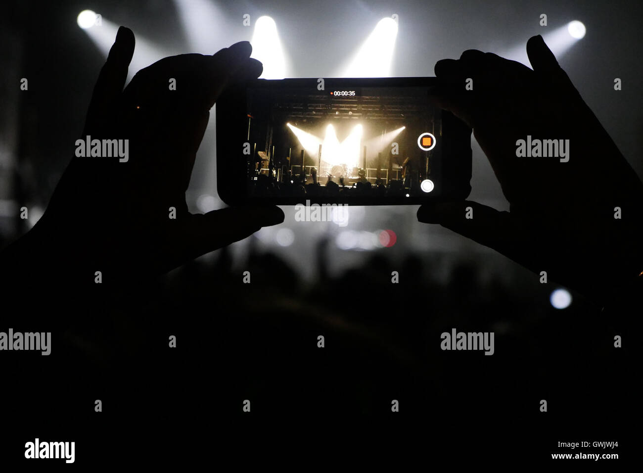 Silhouette of hands recording videos at music concert. Pop music concert with lights, smoke and lots of people Stock Photo