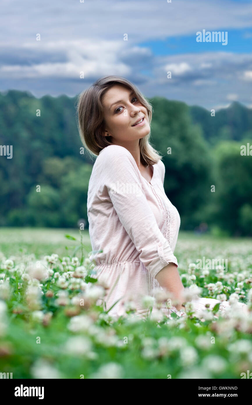 Portrait of young woman sitting on a green lawn Stock Photo - Alamy