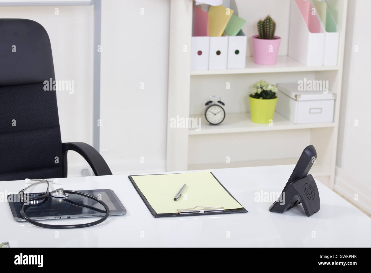 Doctor office table desk and black chair with stethoscope and w Stock