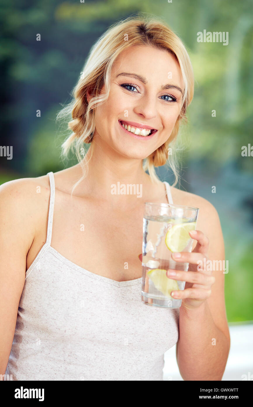 Girl drinking glass of iced water with Lemon Stock Photo