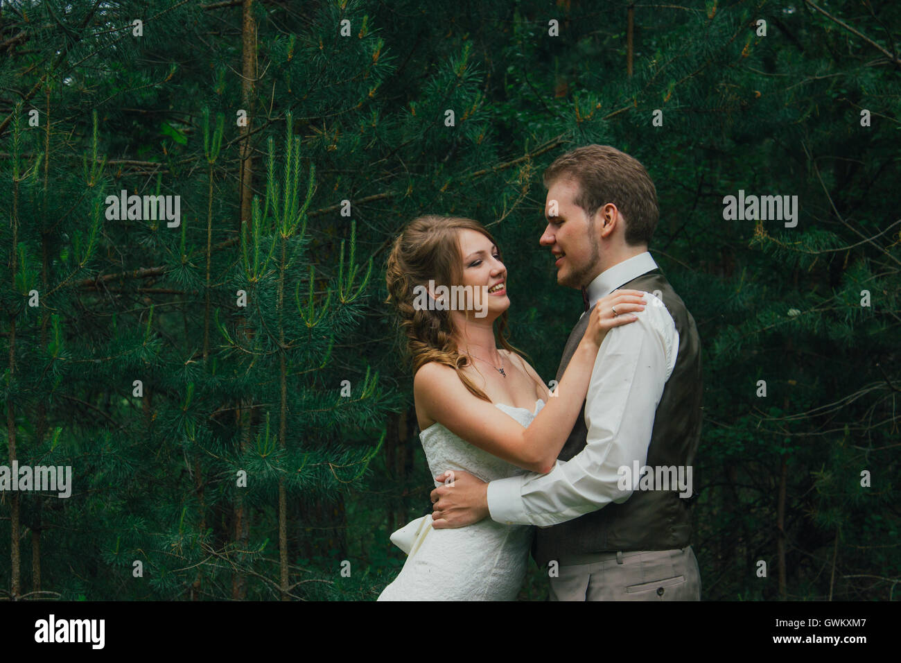 Bride and groom are embracing against the background forest Stock Photo ...