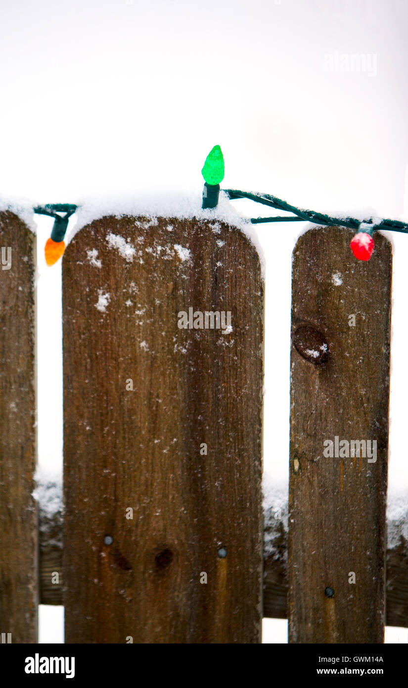Small Christmas lights on a snowy wooden fence Stock Photo