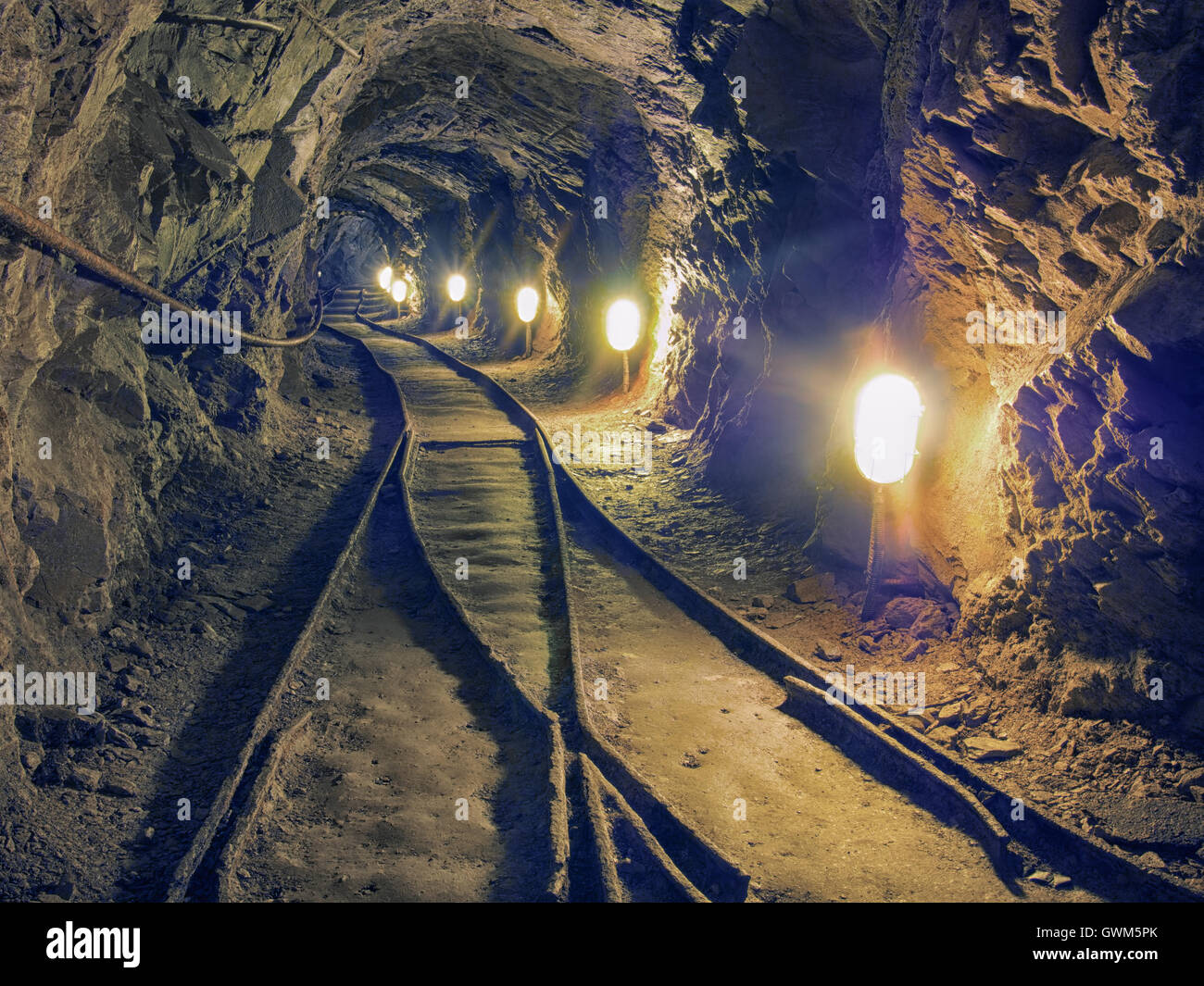 Old mine underground tunnel with rail tracks. Bright light. Stock Photo