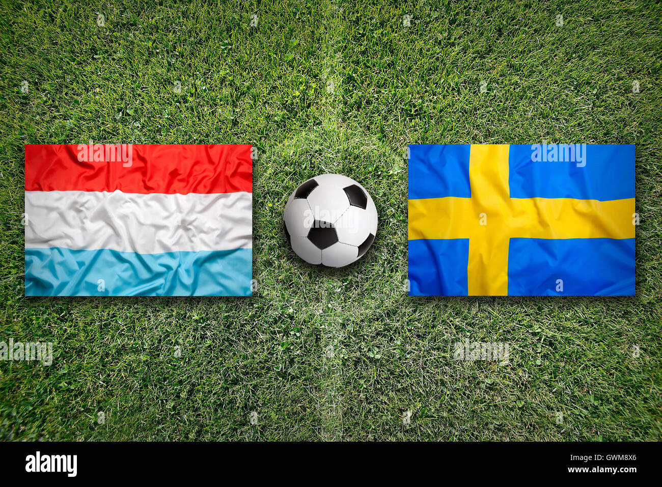 Luxembourg and Sweden flags on a green soccer field Stock Photo