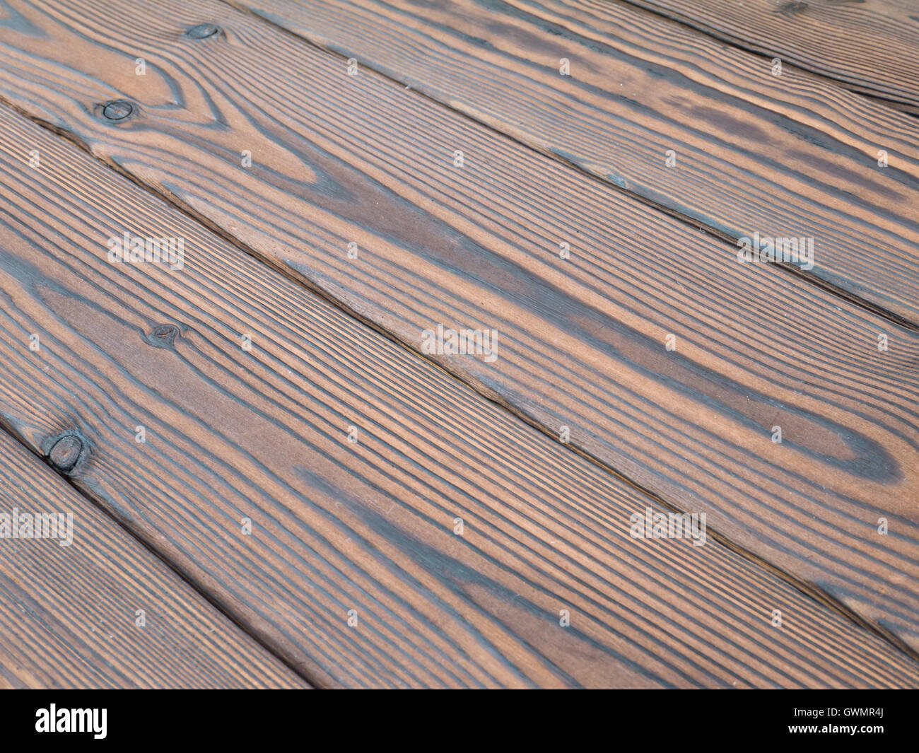 Dark brown textured roasted knotted wooden planks diagonal background Stock Photo
