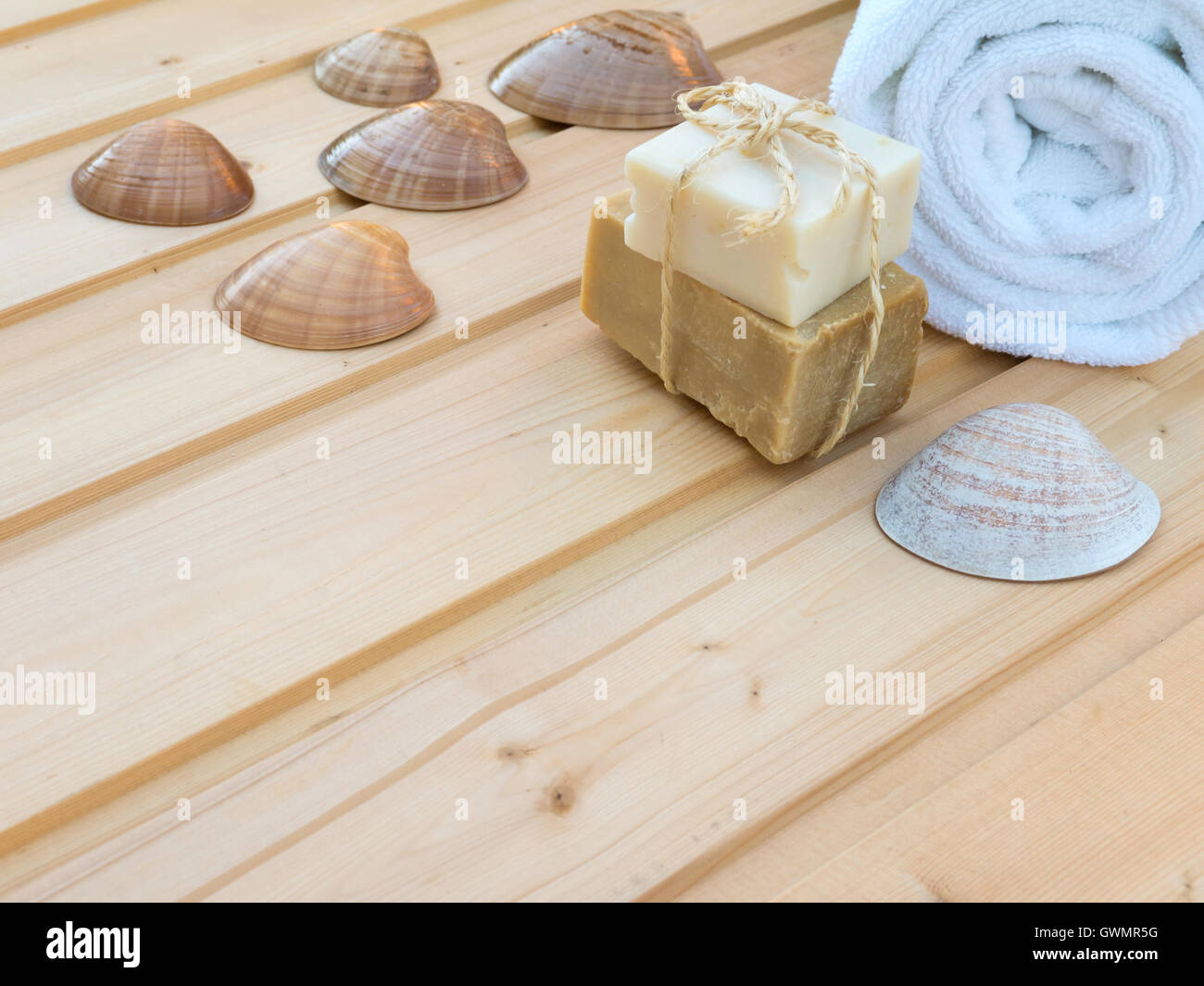White rolled towel, soap bars tied with jute rope and seashells on the