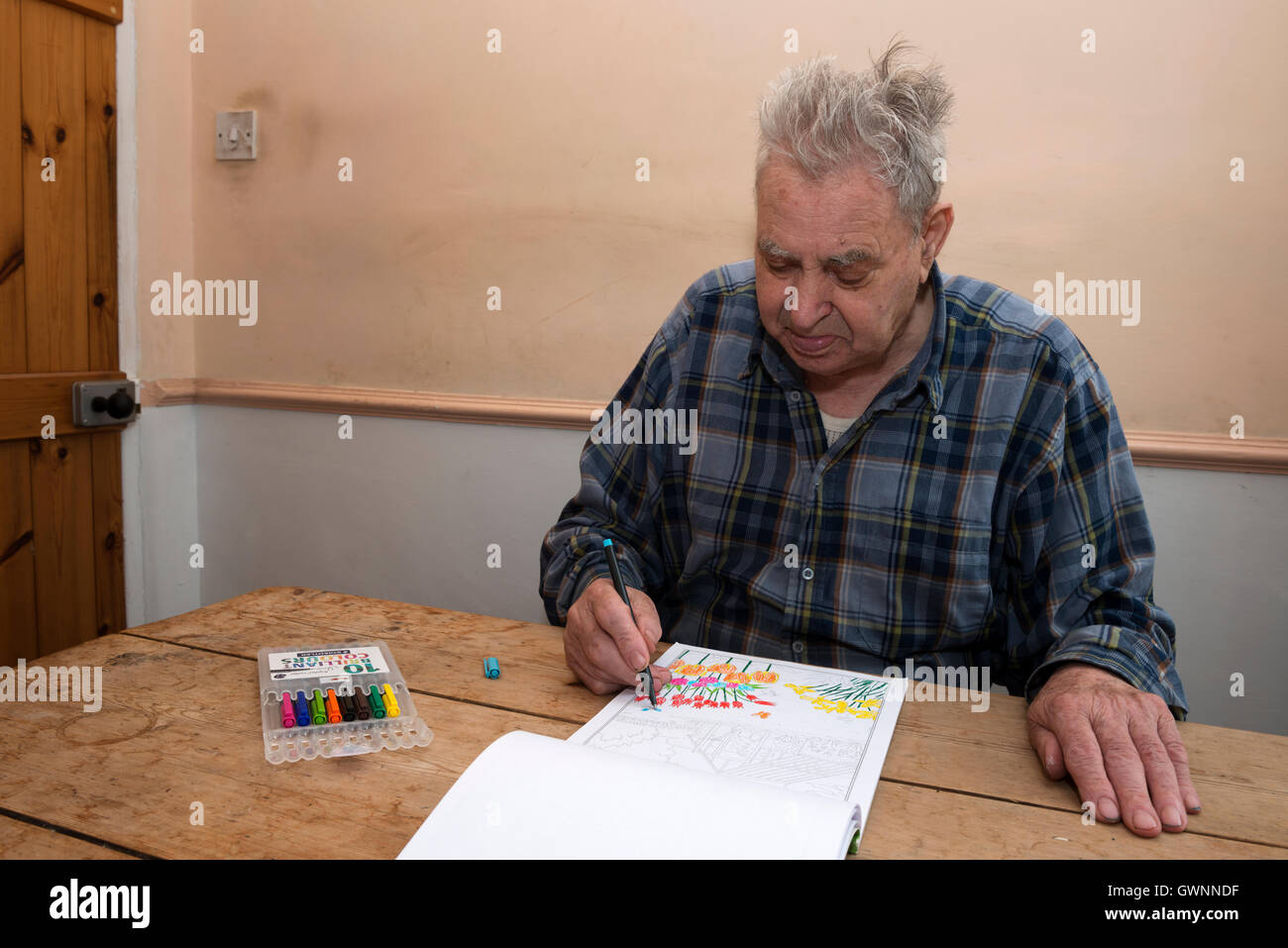 Elderly man colouring-in artwork with felt-tip pens Stock Photo