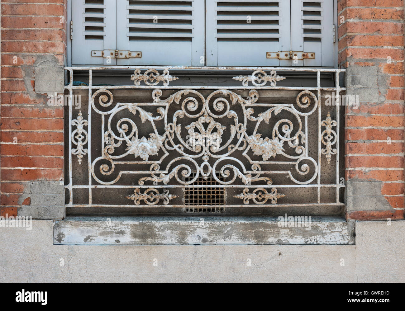 Window with blue shutters and ornate wrought iron window box or balcony on old brick building in Toulouse, France. Stock Photo