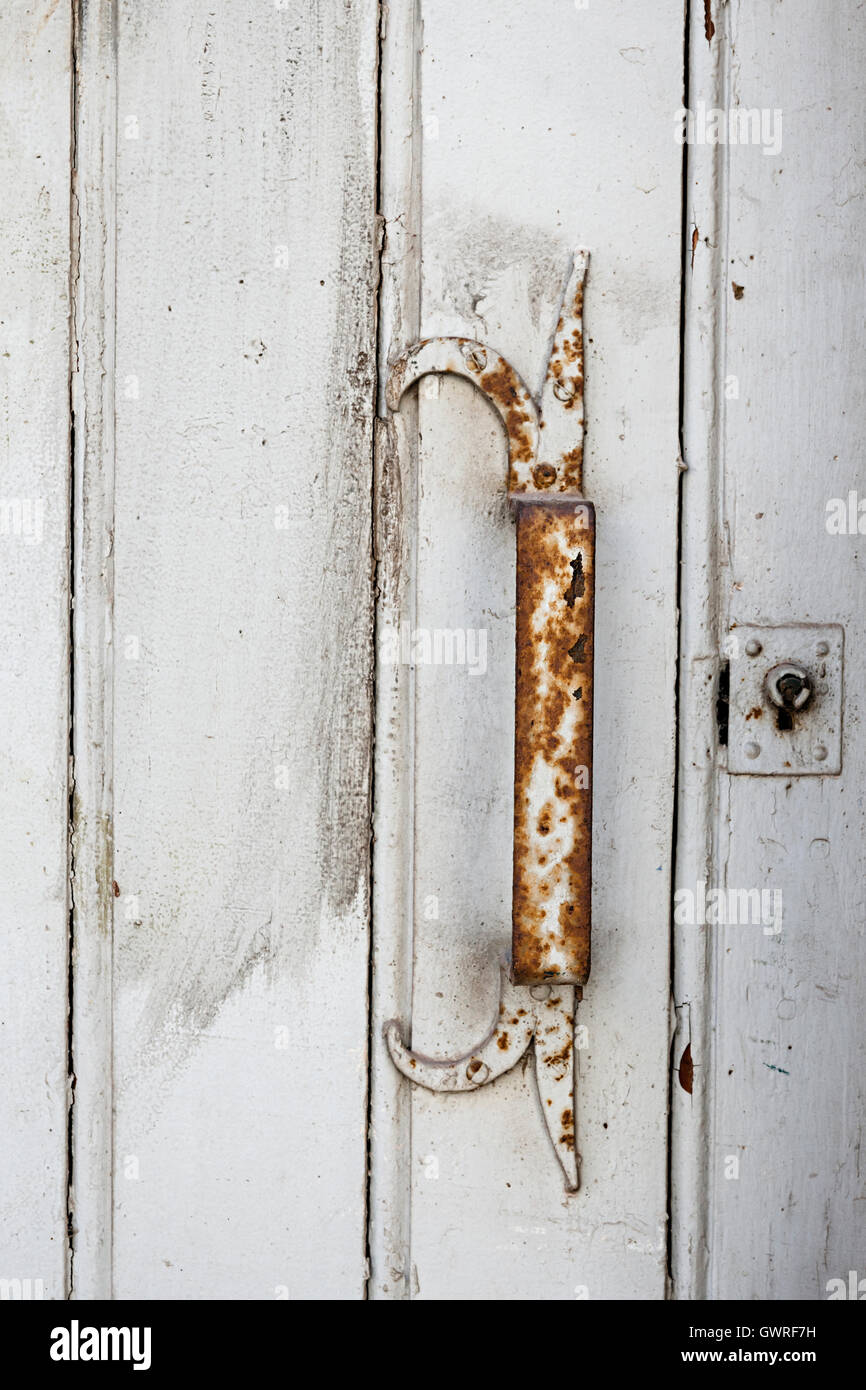 Rusty metal handle on antique painted white wooden door in Toulouse, France, closeup. Stock Photo
