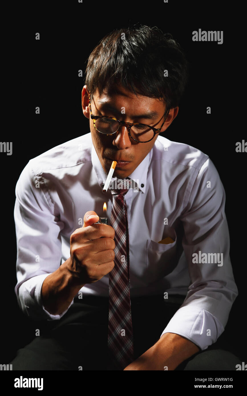 businessman smoking cigarette Young Japanese businessman smoking cigarette Stock Photo