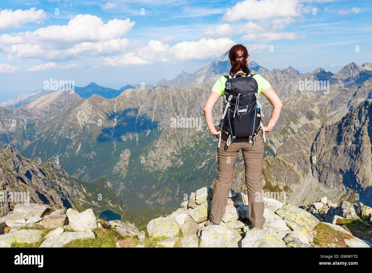 Woman with backpack standing on the edge, looking at Tatry mountains Stock Photo