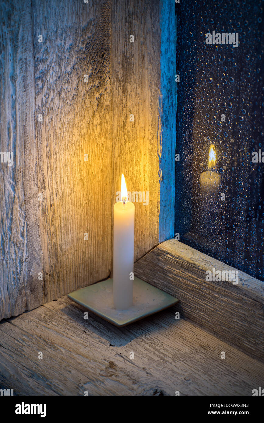 candle on the sill of a window, rain outside Stock Photo Alamy