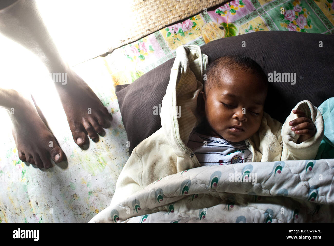 Child sleeping on the ground + feet of his mother ( Madagascar) Stock Photo