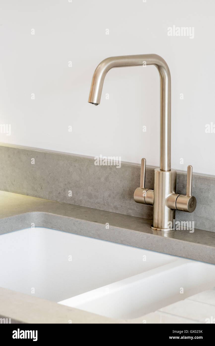 Brushed steel mixer tap with grey worktop and white kitchen sink Stock Photo