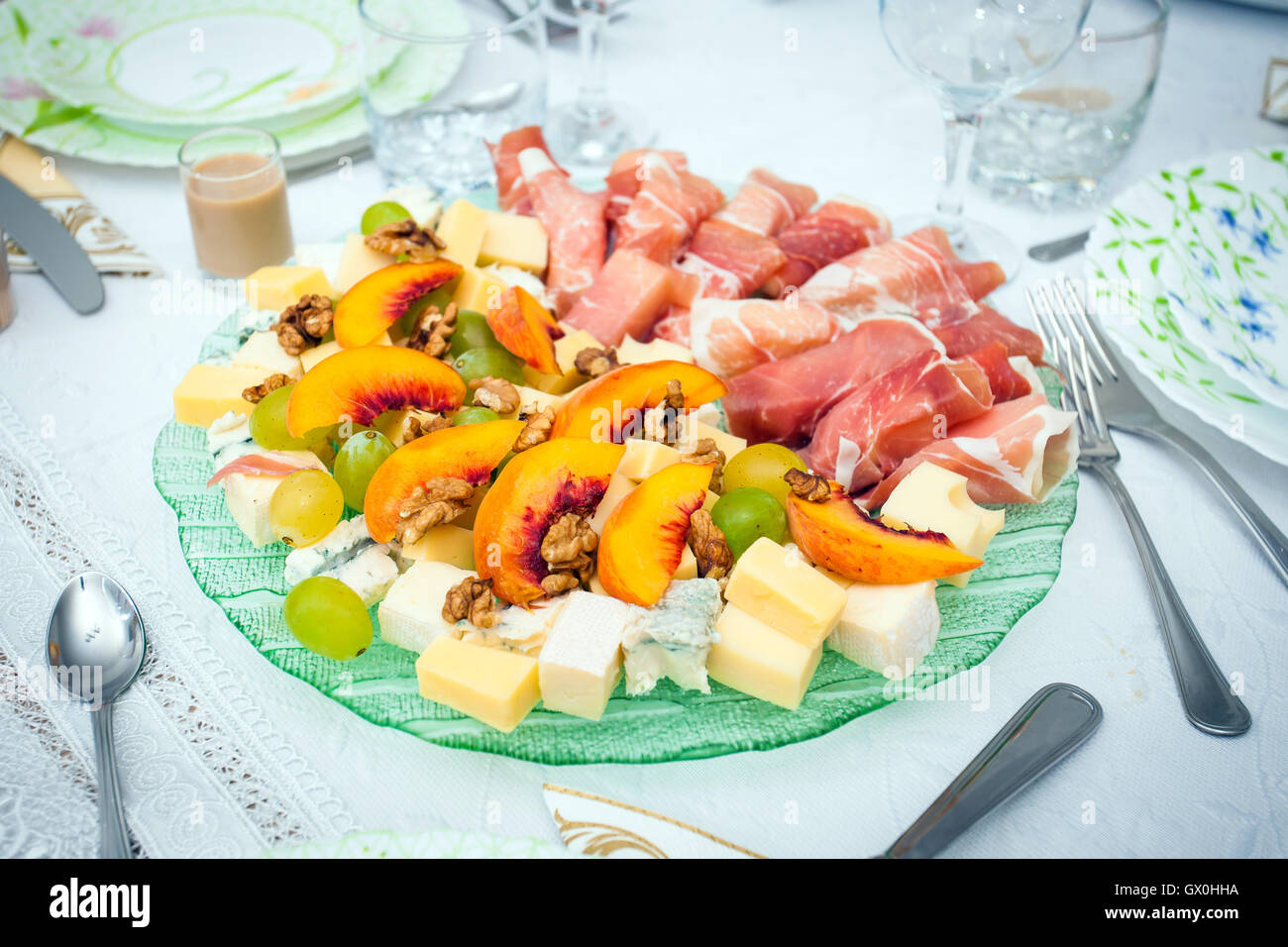 Cocktail food appetizer with ham rolls, peaches, grapes, wallnuts and a variety of cheeses Stock Photo