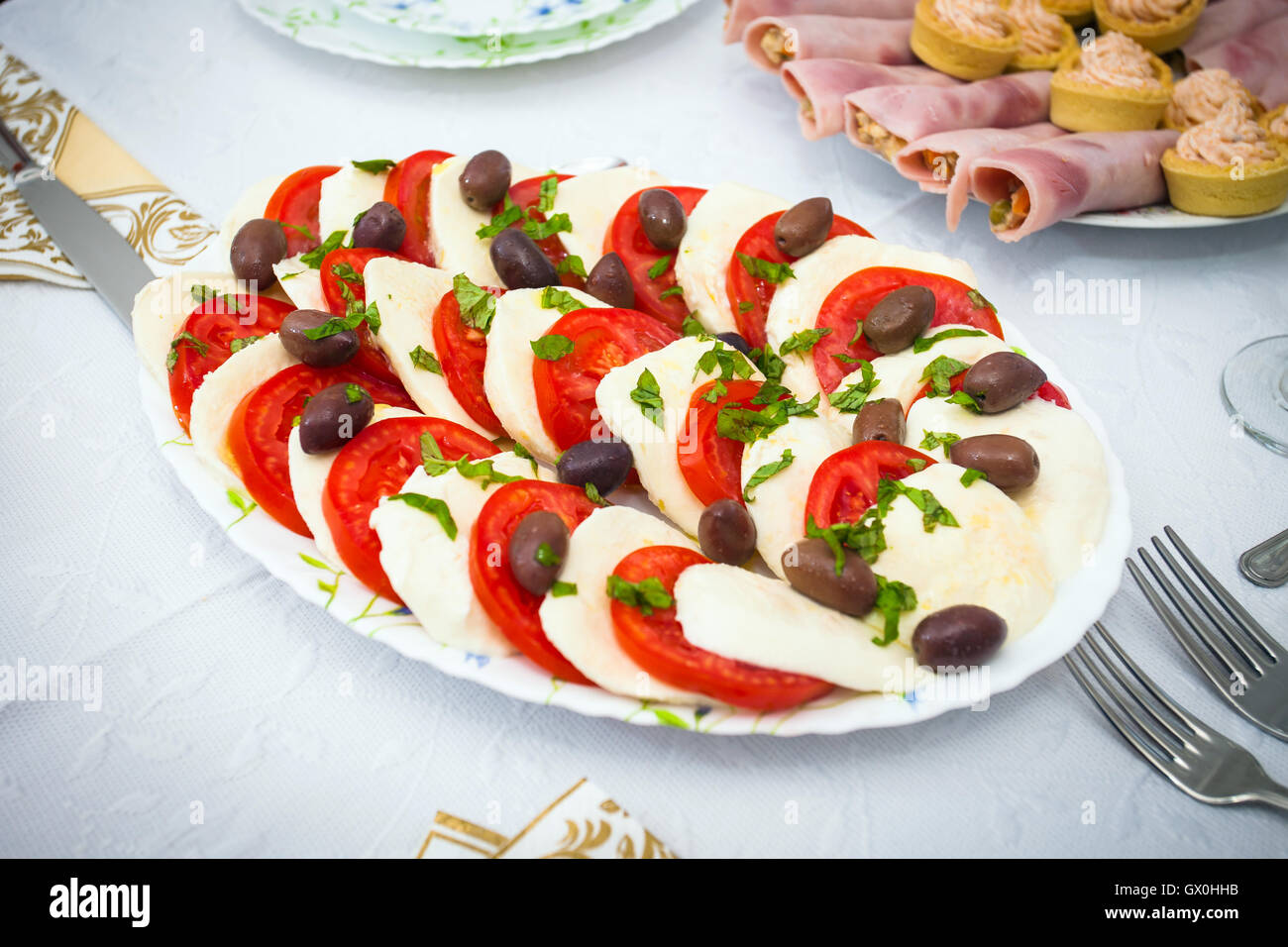 Cocktail food appetizer with slices of mozzarella, tomatoes and olives Stock Photo