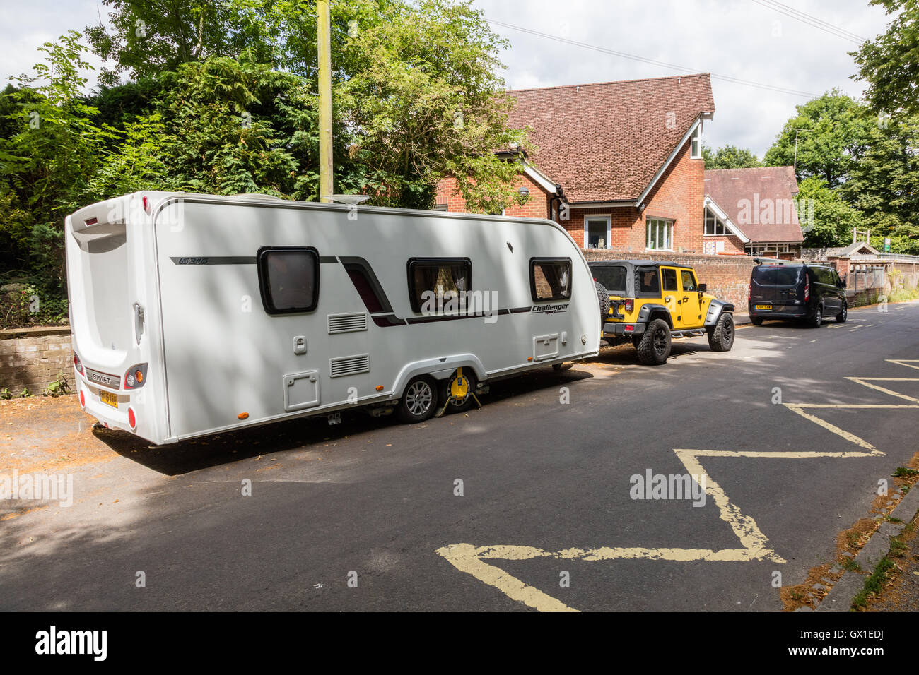 A large caravan and yellow jeep in Chawton Village, Hampshire, UK Stock Photo