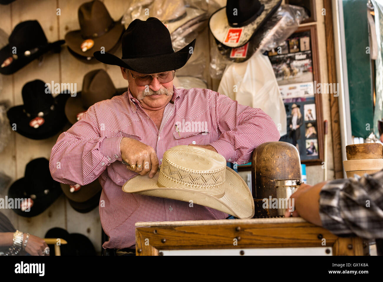 A hat shaper works on customizing a cowboy hat for a customer at