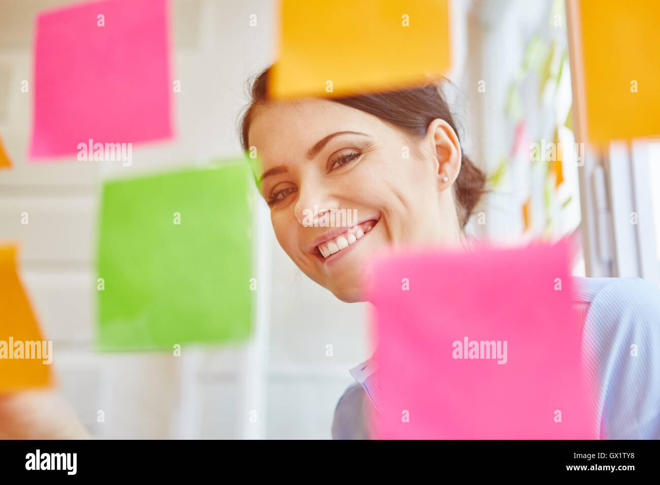 Smiling successful businesswoman gathering ideas on sticky notes Stock Photo