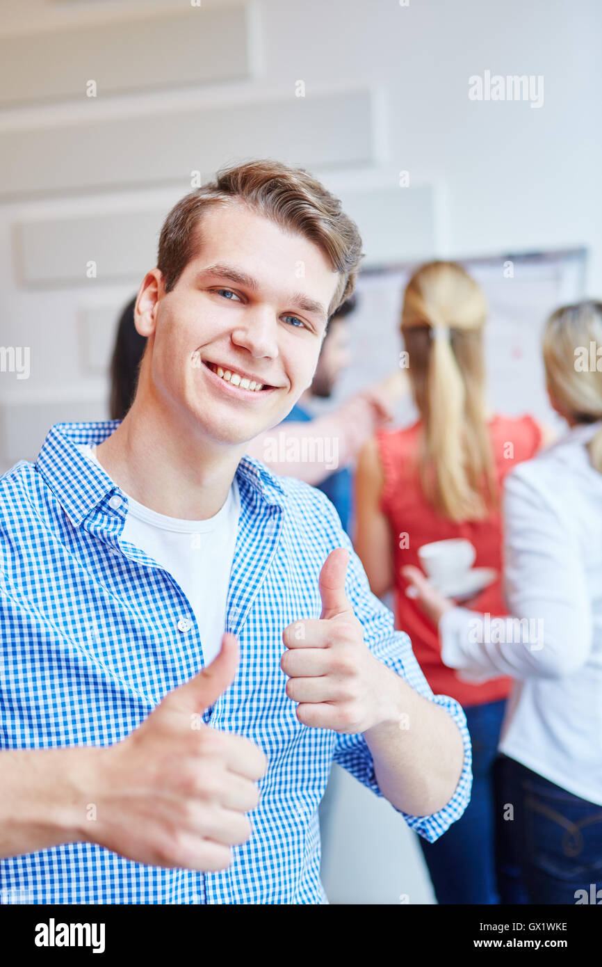 Young student as founder of a start-up holding happily thumbs up Stock Photo