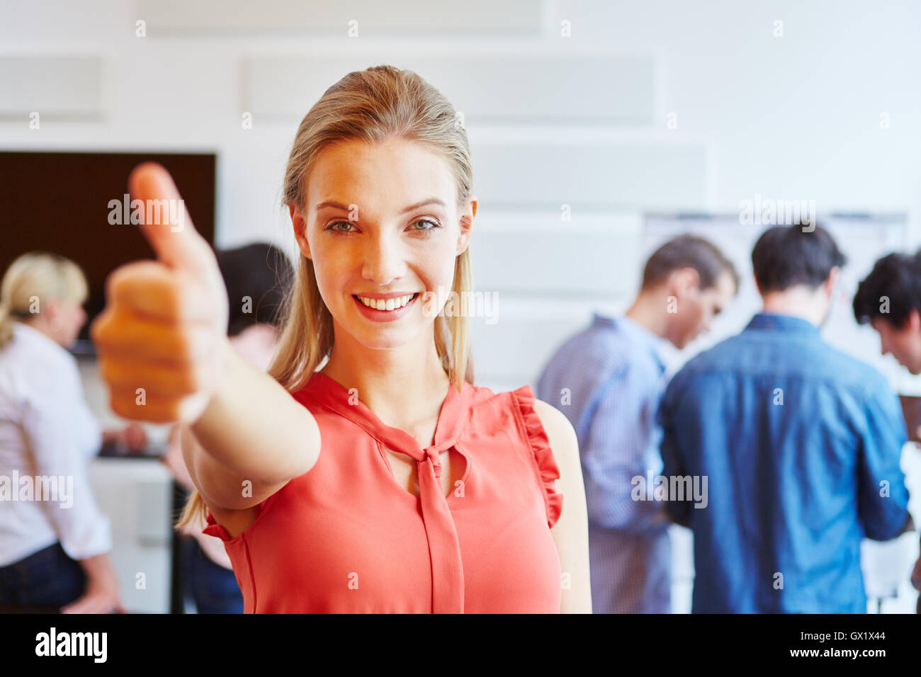 Businesswoman in start-up company holding thumbs up as a sign of success Stock Photo