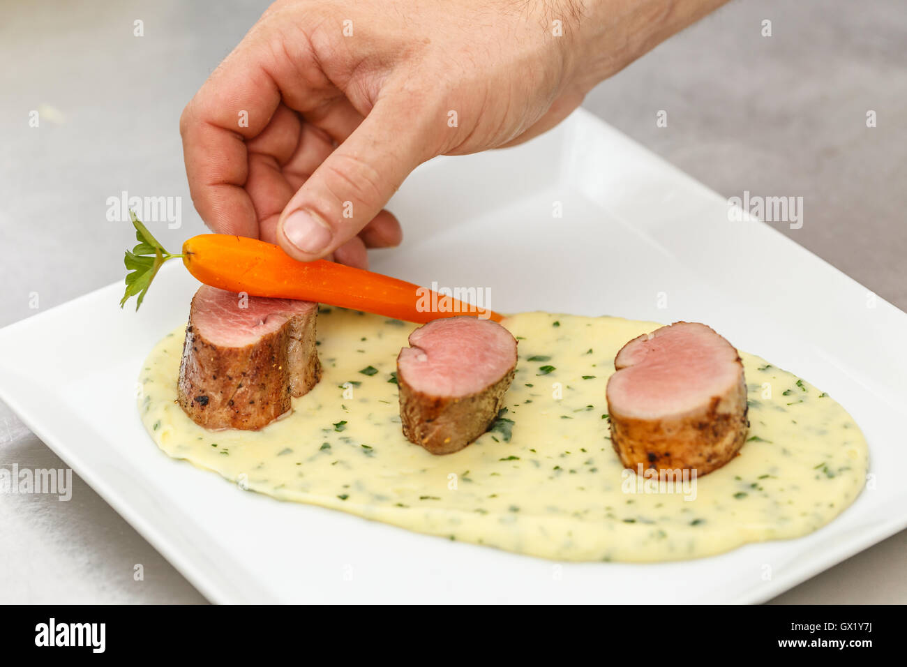 Chef garnishing dish with carrot, fine dining Stock Photo