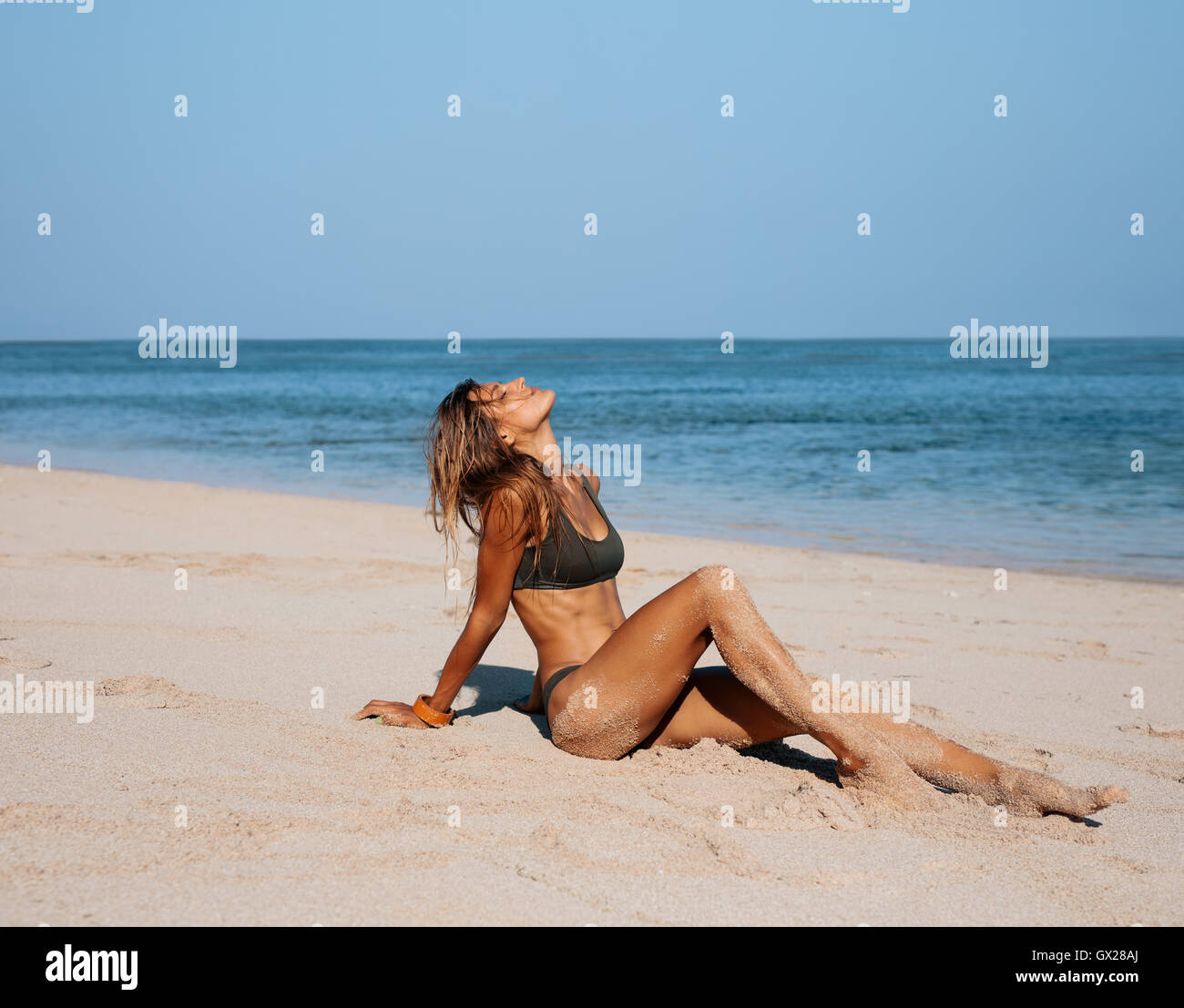 Portrait of beautiful young woman relaxing on beach. Caucasian female model in bikini on sea shore sunbathing. Stock Photo
