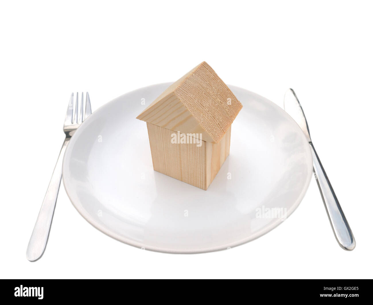 Wooden house of building blocks on the plate with fork and knife isolated on white Stock Photo