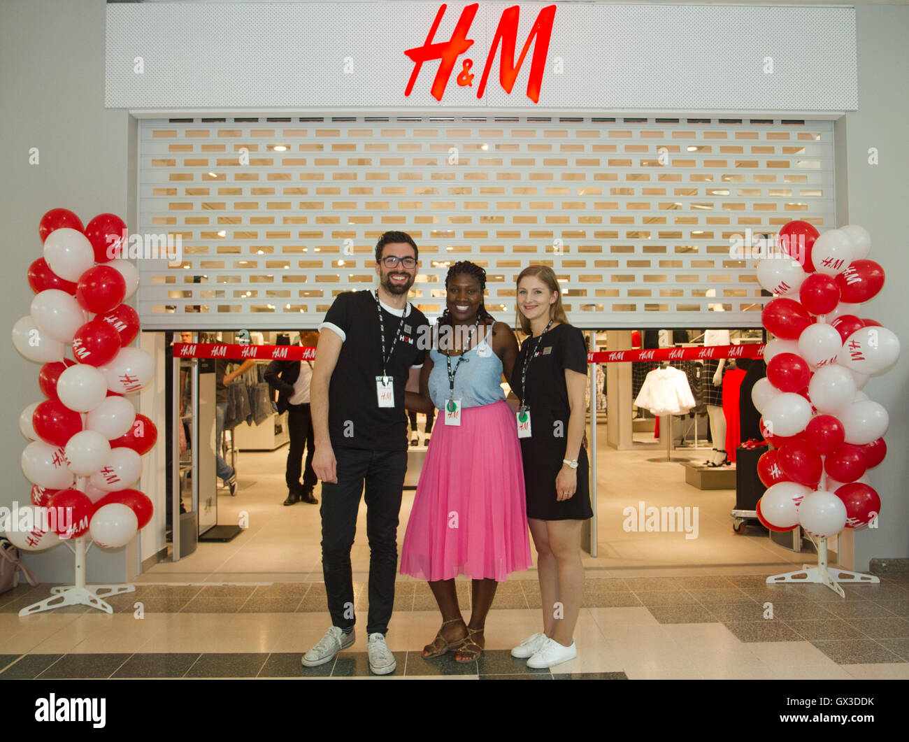 London, UK. 15th September 2016. H&M staff (l-r) Fabrizio, Yanick and Edyta  outside the new H&M store opening in Ilford. Ilford residents and visitors  queue up as a new H&M store opens