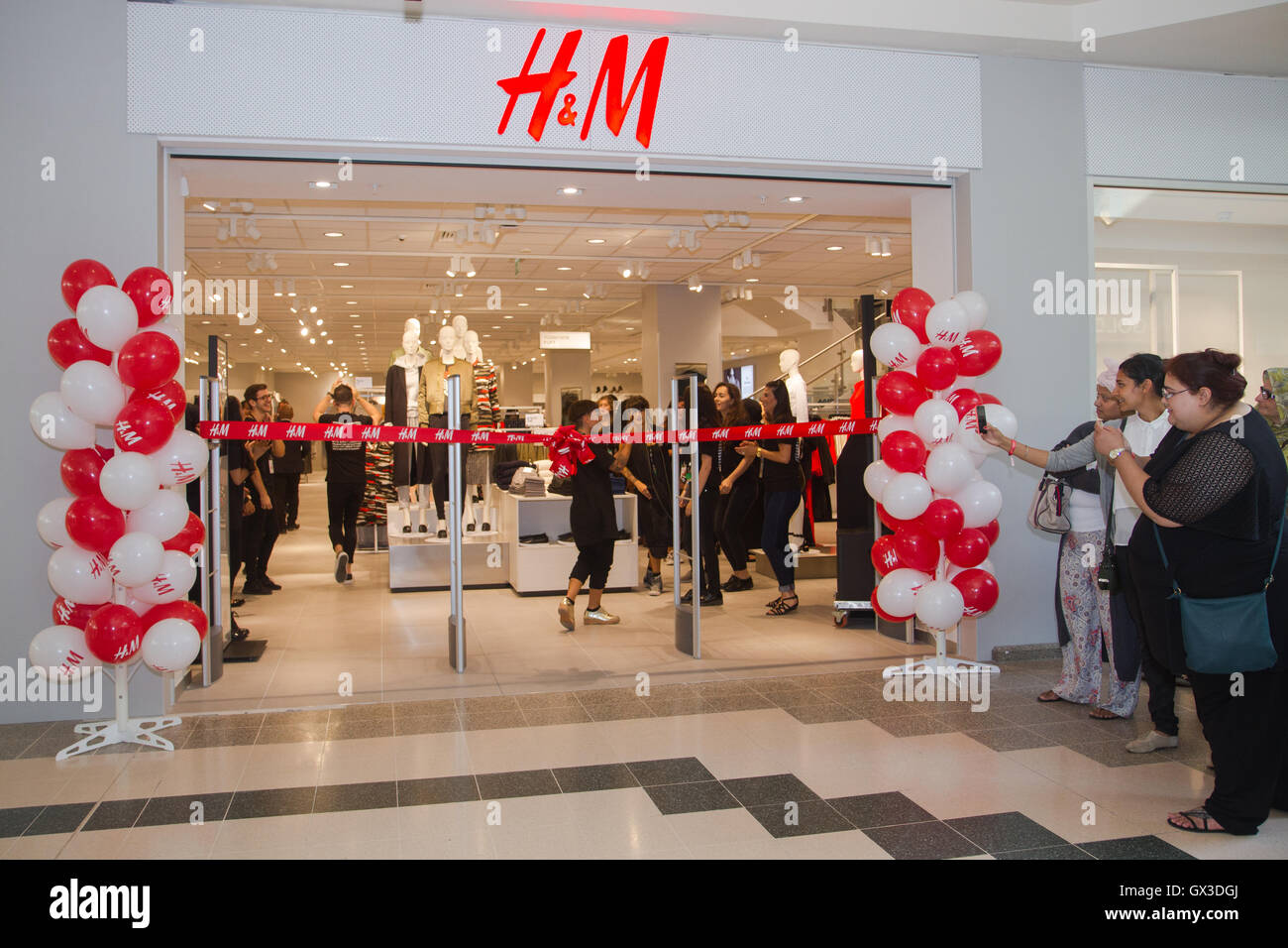 London UK. 15th September 2016. H M staff get ready to welcome Ilford residents and visitors queueing up as a new H M store opens its doors in Exchange Mall Ilford in Essex. Customers